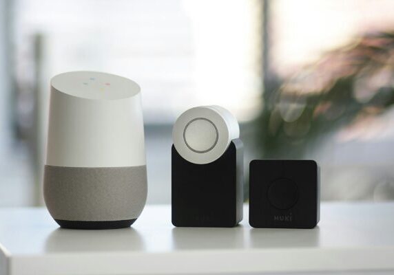 white and gray Google smart speaker and wo black speakers